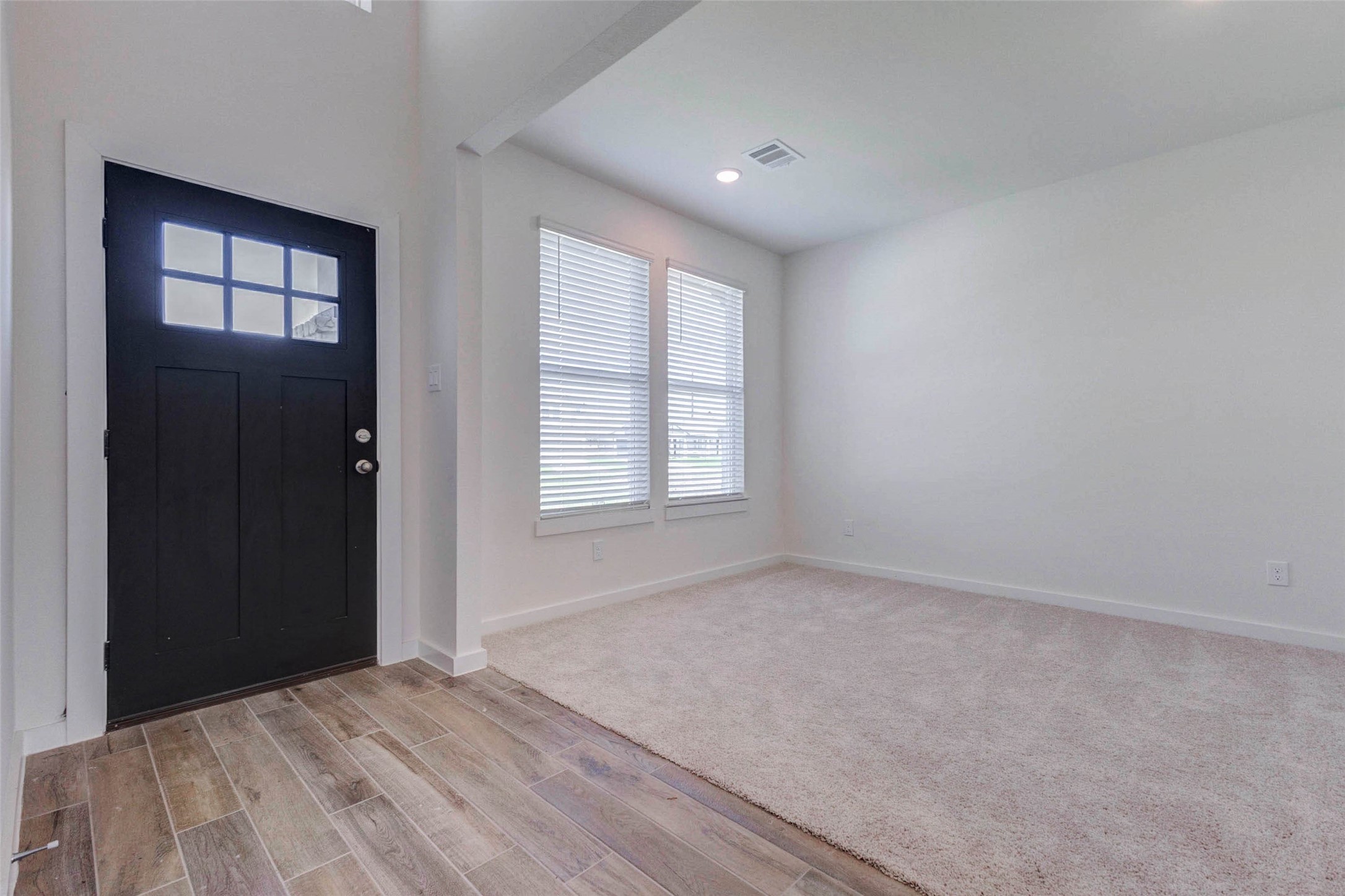 1206 Hemet Court Rosharon, TX 77583 - Photo 3 of 21 Welcoming entry area with a bold black front door, window panel detail, wood-look tile flooring, and a bright adjacent flex space. The soft neutral walls and natural light create a clean, airy first impression. This front room could function beautifully as a formal dining area, sitting room, study, or versatile space tailored to the buyer’s lifestyle.