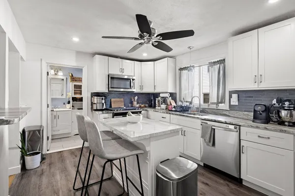 a kitchen with stainless steel appliances granite countertop a dining table chairs refrigerator and cabinets