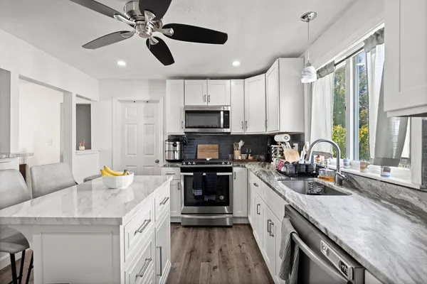 a kitchen with granite countertop a sink stainless steel appliances and cabinets