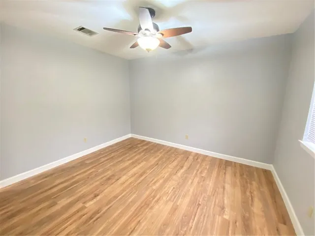 a view of a room with wooden floor and a ceiling fan