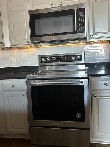 a kitchen with granite countertop white cabinets and stainless steel appliances