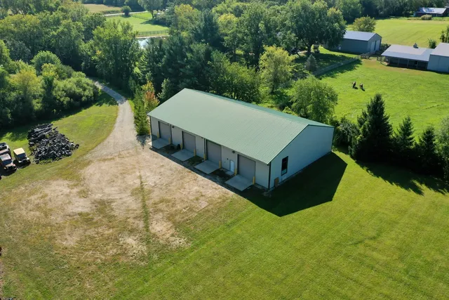 an aerial view of a house with swimming pool and yard with green space