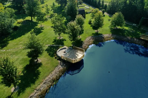an aerial view of a house with a yard lake lake and trees all around