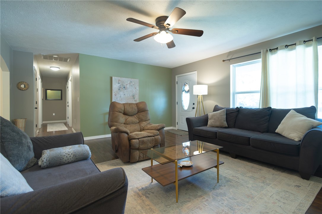 437 Gip Annie Road West Harrison, AR 72601 - Photo 4 of 21 Living space featuring wood-finish flooring, a ceiling fan with light, a front entry door with decorative glass, and a hallway with overhead lighting