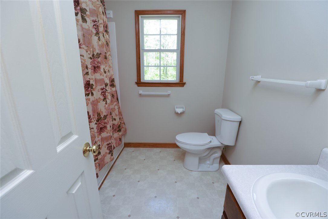 7100 Hair Road Disputanta, VA 23842 - Photo 24 of 40 a white toilet sitting next to a bathroom sink and vanity