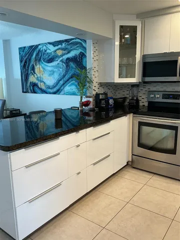 a kitchen with granite countertop white cabinets and black stainless steel appliances
