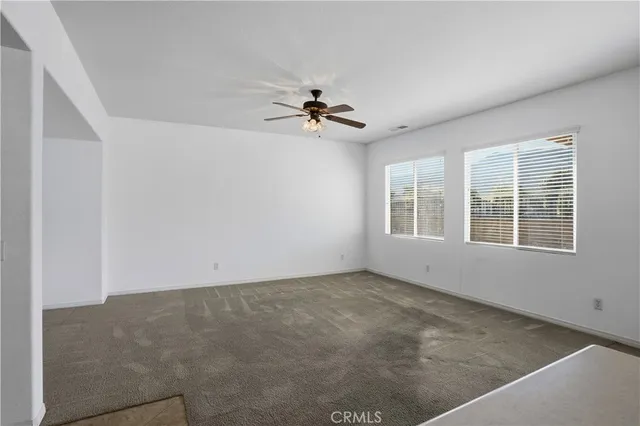 an empty room with windows and ceiling fan