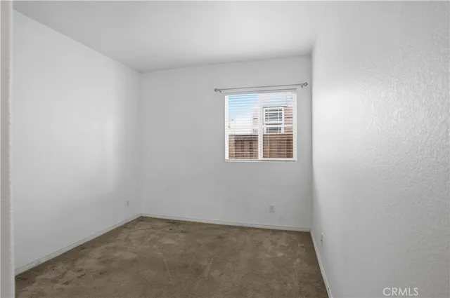 a view of an empty room with closet and a window