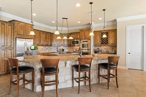 a kitchen with stainless steel appliances kitchen island granite countertop a table chairs and a refrigerator