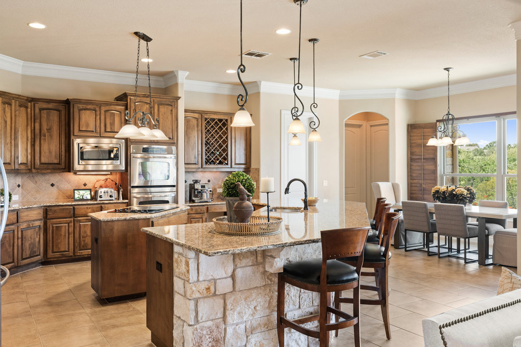 839 Wesley Ridge Drive Spicewood, TX 78669 - Photo 24 of 40 a kitchen with stainless steel appliances granite countertop a stove top oven a sink a dining table chairs and chandelier