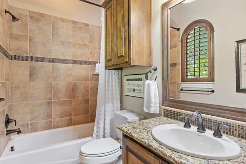 a bathroom with a granite countertop sink a toilet and shower