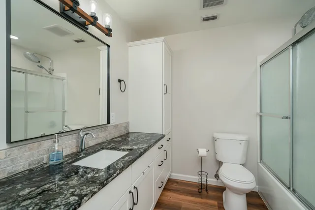 a bathroom with a granite countertop sink toilet and shower