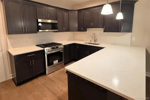 a kitchen with stainless steel appliances a sink a stove a microwave a sink and cabinets