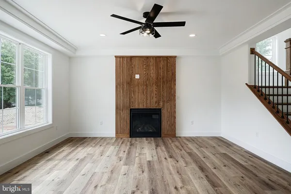 a view of an empty room with wooden floor fireplace and a window