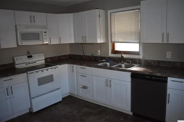 a kitchen with white cabinets appliances a sink and a window