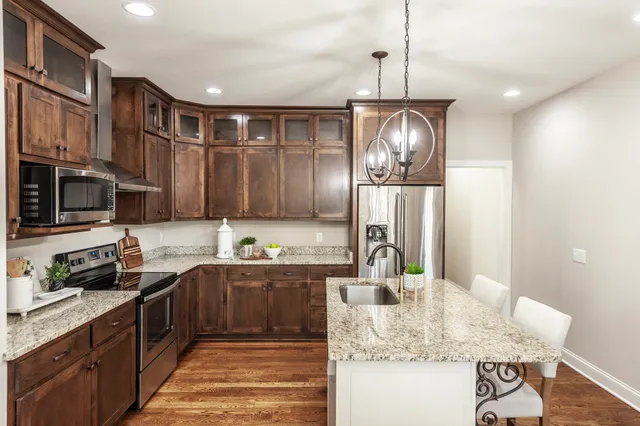 a kitchen with stainless steel appliances granite countertop a sink a stove and a wooden floors