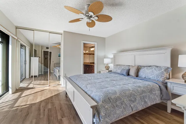a spacious bedroom with a bed a dresser and a chandelier