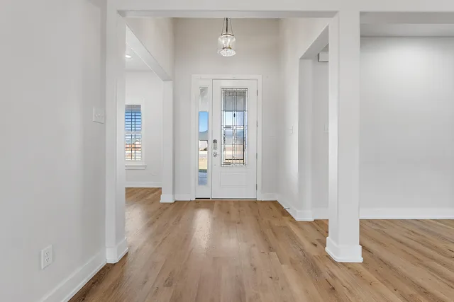 a view of an empty room with a window and a kitchen