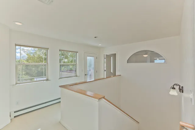a view of an empty room with window and wooden floor