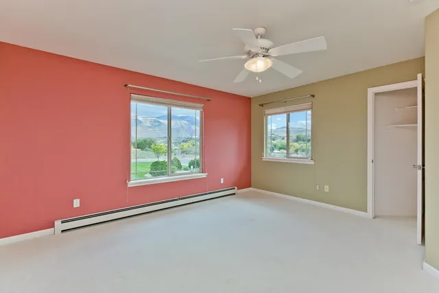 an empty room with windows and fan