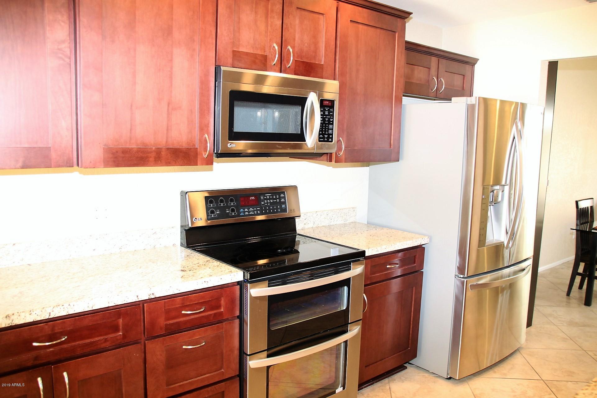 11615 North 40th Way Phoenix, AZ 85028 - Photo 23 of 33 a kitchen with stainless steel appliances a stove a microwave and a refrigerator