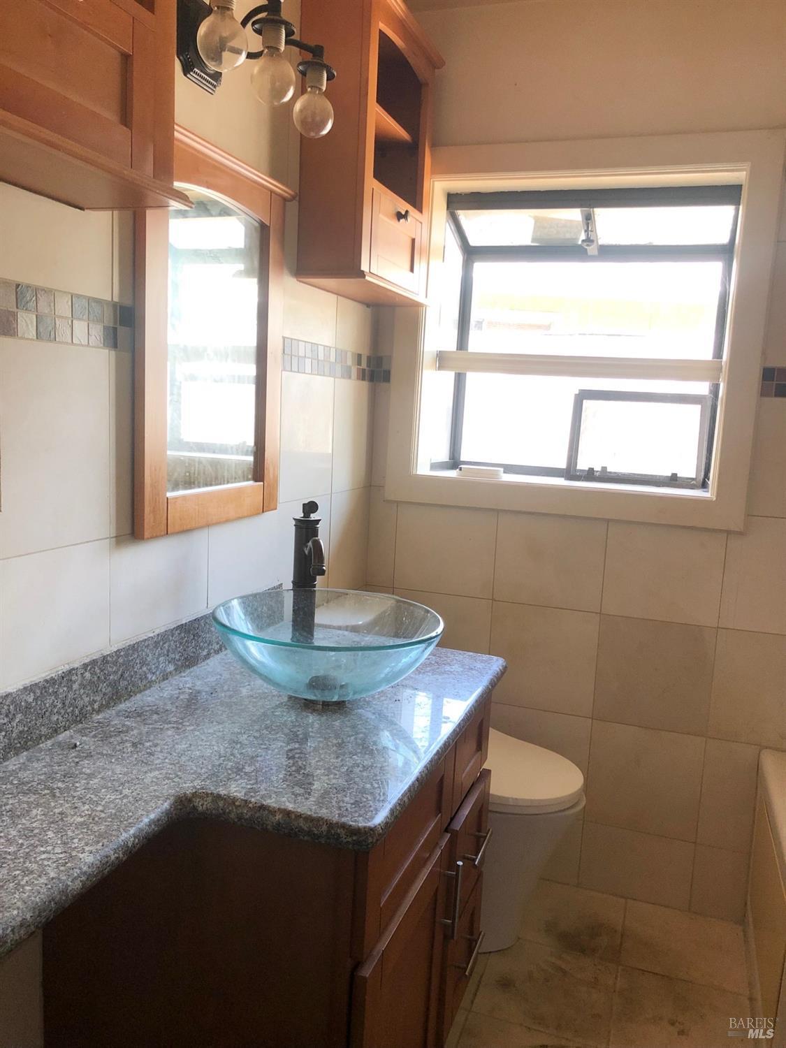 306 Marin Avenue Mill Valley, CA 94941 - Photo 15 of 26 a bathroom with a granite countertop sink a toilet and a window