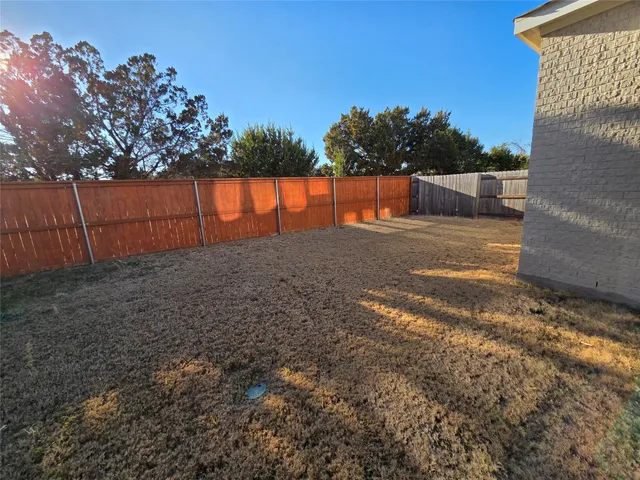 a view of a yard with an tree and wooden fence