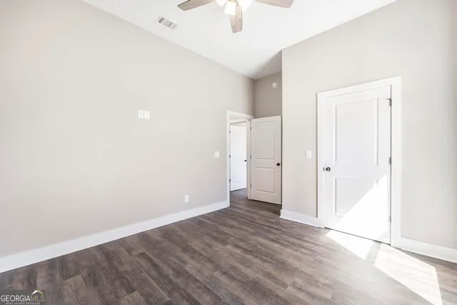 an empty room with a hardwood and ceiling fan
