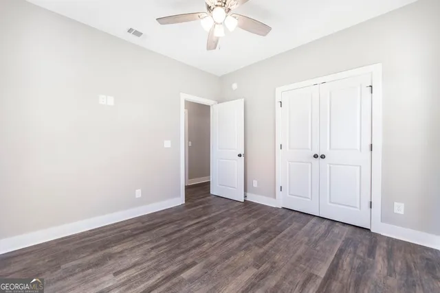 an empty room with wooden floor and ceiling fan