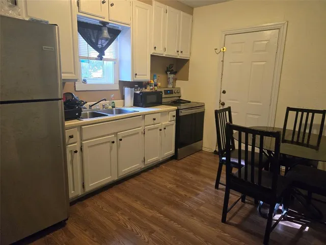 a kitchen with a table chairs refrigerator and cabinets