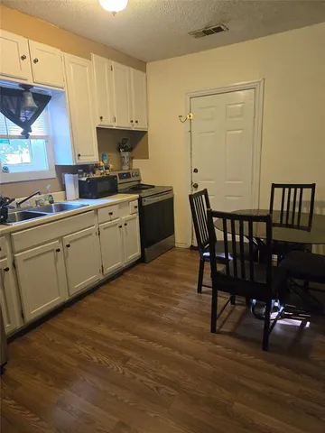 a kitchen with stainless steel appliances granite countertop a table chairs sink and cabinets