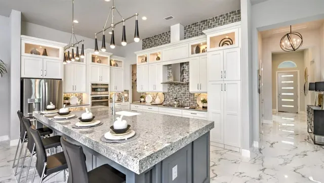 a kitchen with stainless steel appliances granite countertop a table chairs and a refrigerator