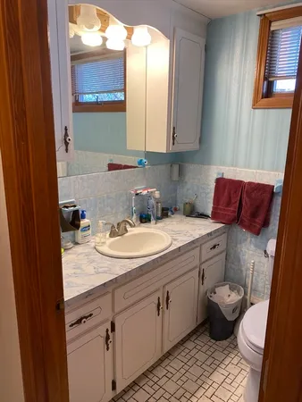 a bathroom with a granite countertop toilet sink and mirror