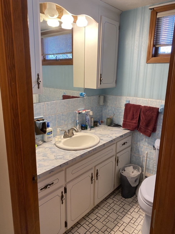 213 Holland Street, Unit R Somerville, MA 02144 - Photo 7 of 23 a bathroom with a granite countertop toilet sink and mirror