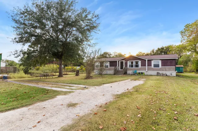 a view of a house with a big yard and large trees