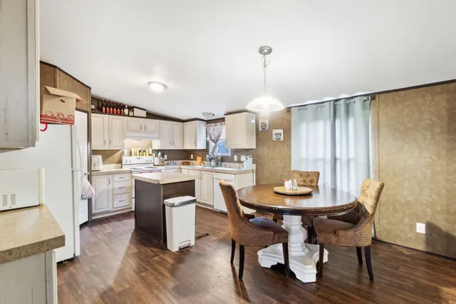 a kitchen with a dining table chairs and refrigerator