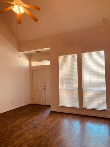 a view of an empty room with window and wooden floor