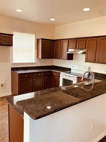 a kitchen with kitchen island granite countertop a sink cabinets and window