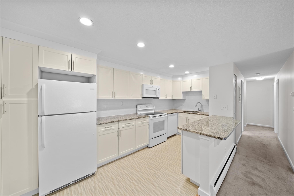50 Green Street, Unit 108 Brookline, MA 02446 - Photo 8 of 22 a kitchen with a refrigerator a sink and white cabinets