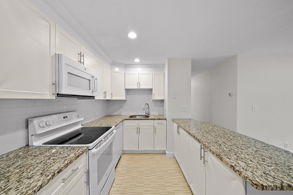 50 Green Street, Unit 108 Brookline, MA 02446 - Photo 9 of 22 a kitchen with a stove top oven and cabinets