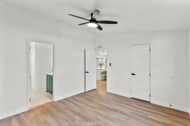 a view of empty room with wooden floor and ceiling fan