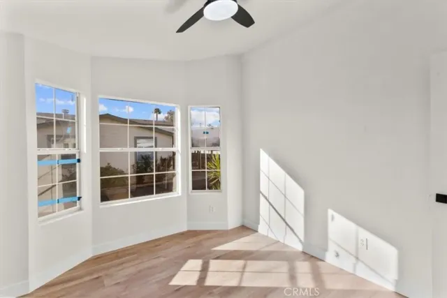 a view of an empty room with wooden floor and windows