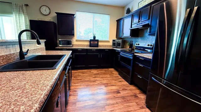 a kitchen with stainless steel appliances granite countertop a stove refrigerator and a sink