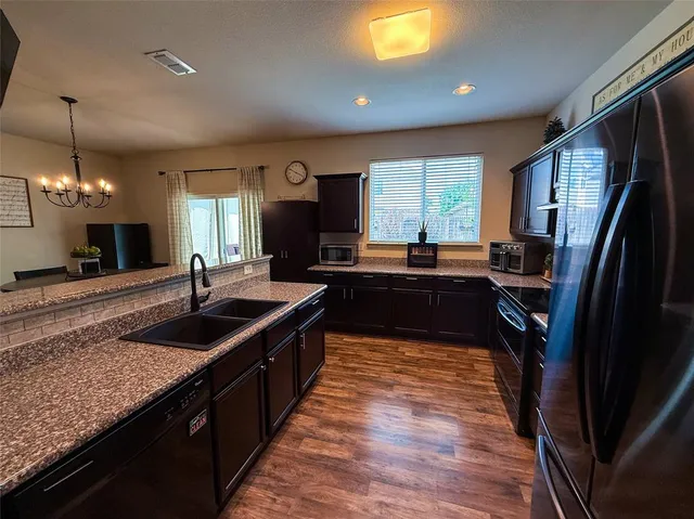 a kitchen with granite countertop a sink stove and refrigerator