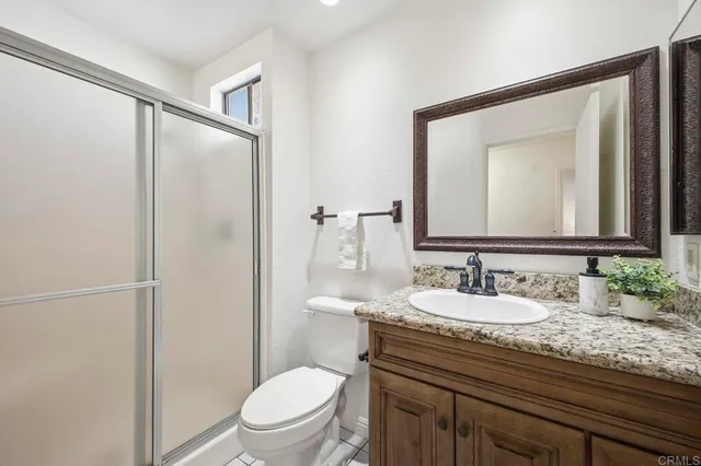 a bathroom with a granite countertop sink toilet a mirror and shower