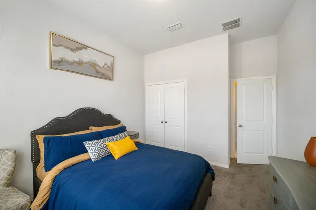 a bedroom with a bed and a lamp on dresser