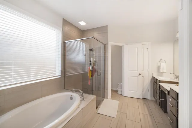 a large spacious bathroom with a tub shower a sink and a mirror