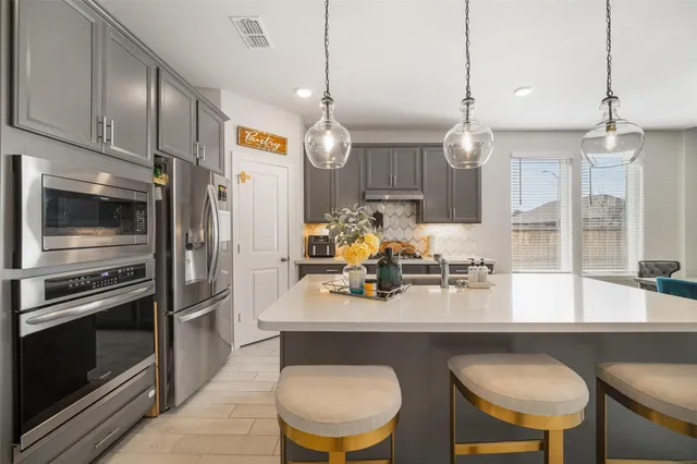a kitchen with a dining table chairs stainless steel appliances and cabinets