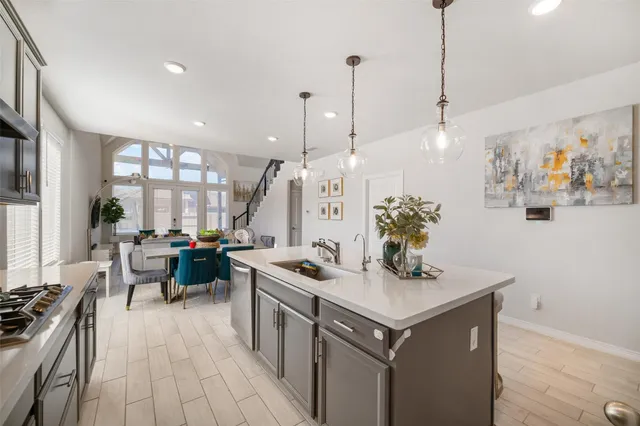 a kitchen with a stove a sink a counter top space and living room view