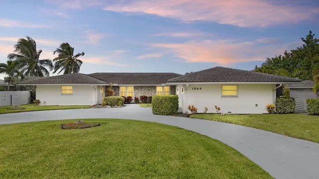 a front view of a house with a yard and potted plants